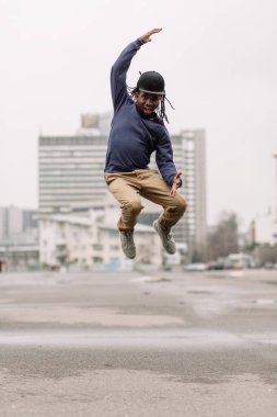 Yakışıklı Afrika kökenli Amerikalı dreadlocks kahverengi pantolon ve başını evleri, arka planı siyah şapkalı Mavi kazak ile şehir