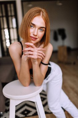 Güzel tatlı kız profesyonel kamera poz. Kısa kırmızı saçlı altın şık model, dolgun dudaklar, rahat giyim, kostüm, kıyafet, sütyen. Model testi, giyim reklam