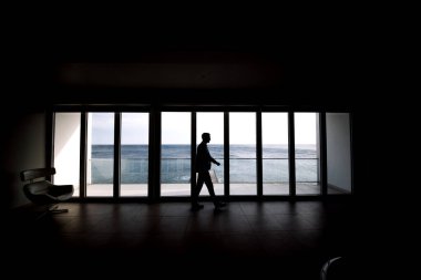 Ufuktaki ofisteki bir adamın silüeti, panoramik pencereler.