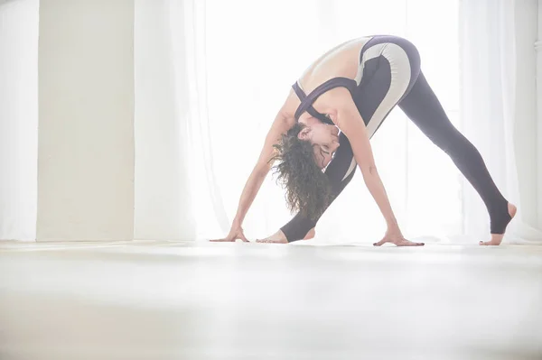 Schöne junge Frau praktiziert Yoga asana parivrtta trikonasana - Drehdreieck-Pose im Licht-Yoga-Studio — Stockfoto