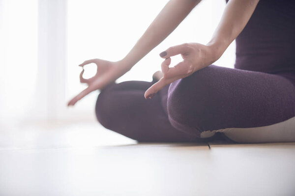 Closeup of womans hands meditating in light yoga studio