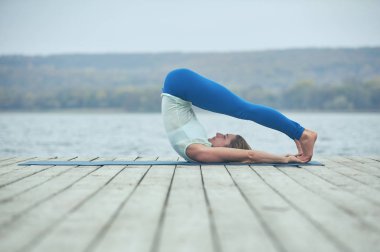Güzel ve genç birbayan uygulamaları yoga asana Shirshasana - başı poz göl yakınındaki ahşap güverte
