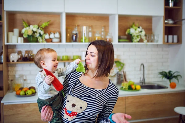 Gelukkig jongedame, houden een 1-jarige kind en samen koken in de keuken — Stockfoto