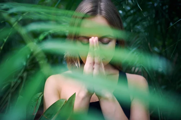 Aranyos fiatal nő meditál, és ezzel namaste portréja kéz a dzsungelben. Süt a nap — Stock Fotó