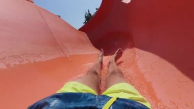 Güneşli bir yaz gününde turuncu su kaydırağından kayarak kayan ve Aquapark 'taki kıvrımlardan geçen kişinin POV videosu..
