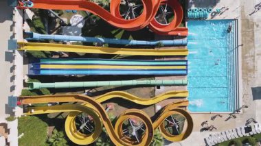 Aerial view of a colorful water park with multiple slides, pools, and people enjoying summer activities on a sunny day.