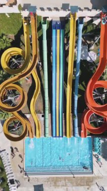 Aerial view of a colorful water park with multiple slides, pools, and people enjoying summer activities on a sunny day.