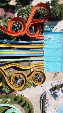 Aerial view of a colorful water park with multiple slides, pools, and people enjoying summer activities on a sunny day.