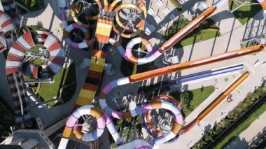 Renkli slaytlarla, tembel nehirlerle, havuzlarla ve dinlenme yerleriyle dolu canlı bir su parkının hava görüntüleri. Aileler ve turistler, modern bir tatil köyünde yaz eğlencesinin tadını çıkarıyorlar..