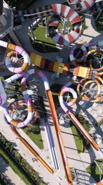 Renkli slaytlarla, tembel nehirlerle, havuzlarla ve dinlenme yerleriyle dolu canlı bir su parkının hava görüntüleri. Aileler ve turistler, modern bir tatil köyünde yaz eğlencesinin tadını çıkarıyorlar..