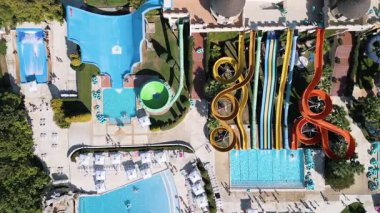 Renkli slaytlar, havuzlar, sıçrama bölgeleri ve rahatlama alanlarıyla dolu devasa bir su parkının çarpıcı görüntüsü. İnsanlar heyecan ve eğlence dolu güneşli bir günün tadını çıkarırlar..