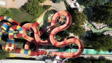 Su parkında şişme borulara binen insanların renkli su kaydıraklarının havadan görünüşü. Parlak yaz günü heyecan, eğlence ve heyecanla dolu..