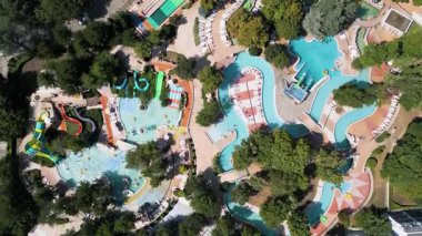 Güneşli bir yaz günü güneşli bir günde güneşli yataklar ve ağaçlarla çevrili havuz, tembel nehirler ve küçük slaytlarla dolu rahatlatıcı bir su parkı manzarası..