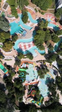 Güneşli bir yaz günü güneşli bir günde güneşli yataklar ve ağaçlarla çevrili havuz, tembel nehirler ve küçük slaytlarla dolu rahatlatıcı bir su parkı manzarası..