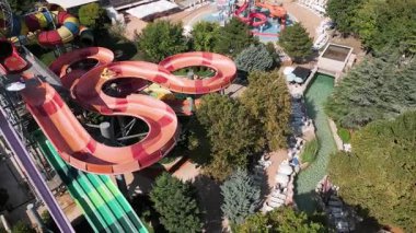 Su parkında şişme borulara binen insanların renkli su kaydıraklarının havadan görünüşü. Parlak yaz günü heyecan, eğlence ve heyecanla dolu..