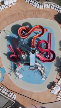 Renkli çocukların su parkının hava manzarası. Kaydıraklı slaytlar, sığ havuz ve eğlenceli bir su parkında güneşin altında oynayan çocuklar.