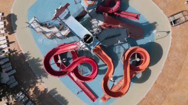 Renkli çocukların su parkının hava manzarası. Kaydıraklı slaytlar, sığ havuz ve eğlenceli bir su parkında güneşin altında oynayan çocuklar.