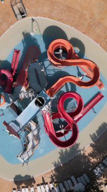 Renkli çocukların su parkının hava manzarası. Kaydıraklı slaytlar, sığ havuz ve eğlenceli bir su parkında güneşin altında oynayan çocuklar.