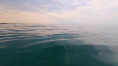 Slow motion video of calm evening sea with gentle ripples and soft pastel reflections. Tranquil ocean surface under a serene sky, creating a peaceful and meditative mood.