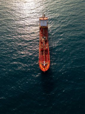 Top-down aerial video of a red oil tanker ship floating in the open sea. Industrial marine vessel captured in bright daylight, showing deck structures and equipment in detail.