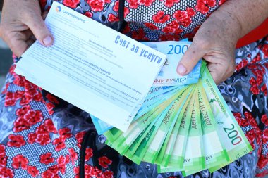 Elektrik ve yaşlı bir kadını elinde Rus parası için okundu bilgisi
