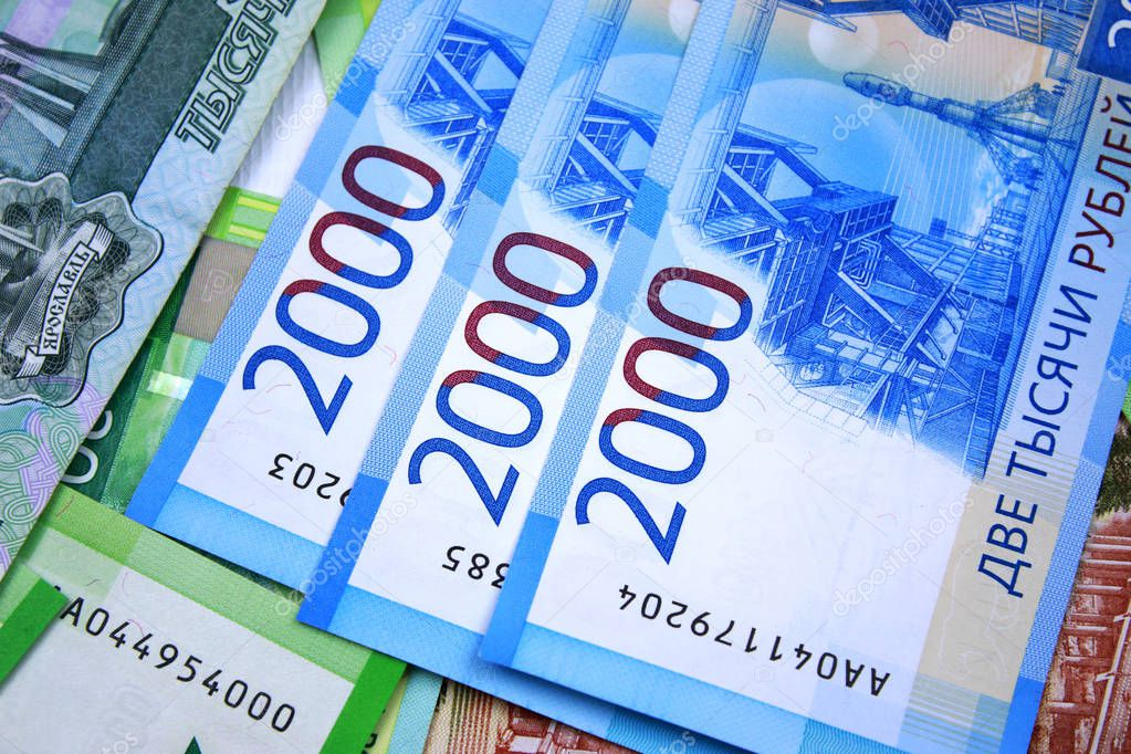 Three new bills with a nominal value of 2000 rubles on the background of mone