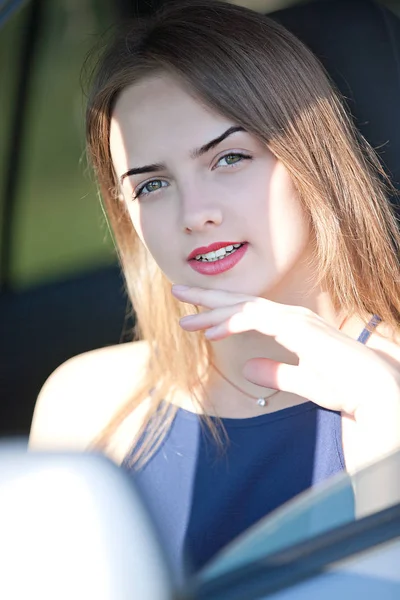 夏の太陽に照らされた乗用車の運転席に座っている美しい少女 — ストック写真