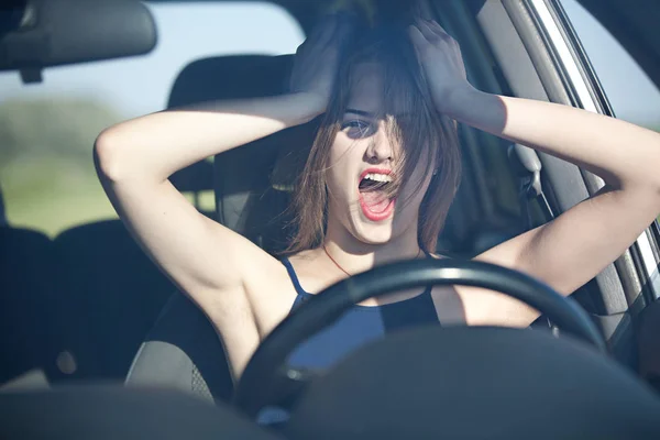 Screaming woman at the wheel of a car during the crash, hands clutching her head, view through the windscreen