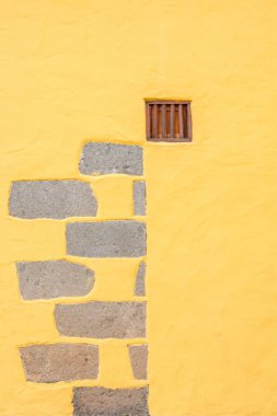 Sarı duvar taş ve küçük bir pencere ile dekore edilmiş
