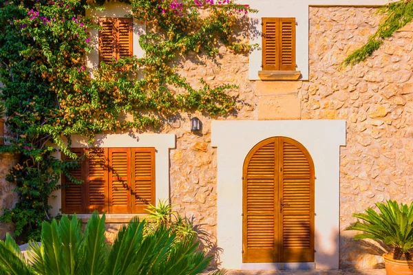 The facade of an old stone house with wooden brown shutters. Majorca. Spain.