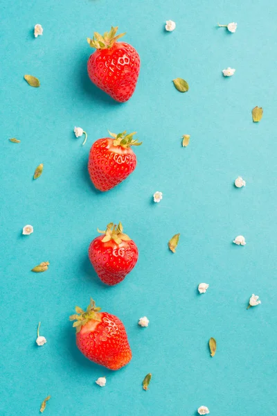 Strawberry creative pattern. Ripe red berry with green leaves on blue background