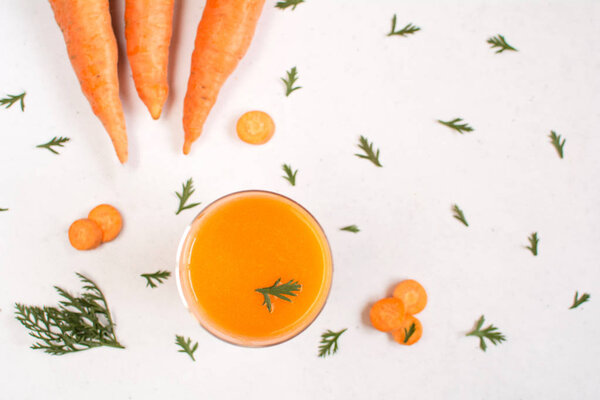 Glass of carrot juice and carrots on a white background. 