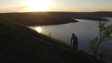 Nehir kıyısında kenarında bir siluet içinde güzel gün batımı hiking bir adam hava epik çekim.