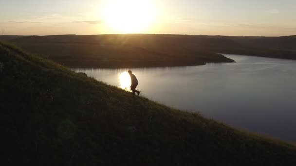 Nehir kıyısında kenarında bir siluet içinde güzel gün batımı hiking bir adam hava epik çekim. — Stok video