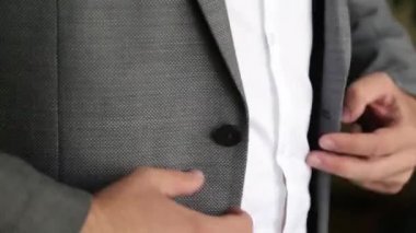 Damat ceketini ilikliyor. Takım elbiseli şık bir adam ceketinin düğmelerini bağlıyor ve dışarı çıkmaya hazırlanıyor..