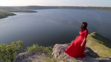 Büyük nehir banka kenarında kamera için poz kırmızı elbiseli güzel siyah saçlı kadın.