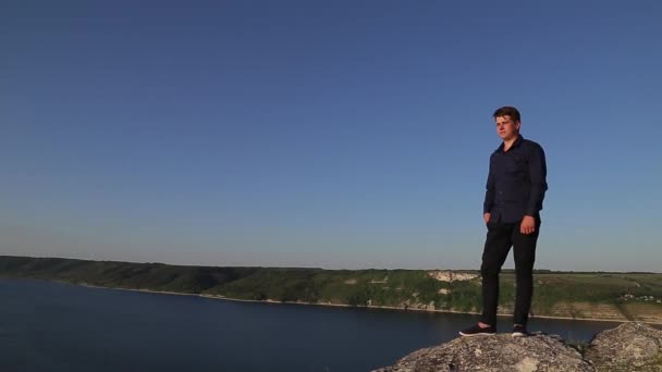 Aantrekkelijke jongeman poseren voor de camera aan de rand van het land. — Stockvideo