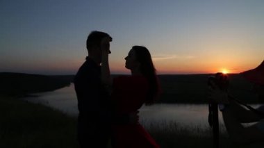Nehir kenarında öpüşme aşık çift çekim kameramanlar. Günbatımı ışık.