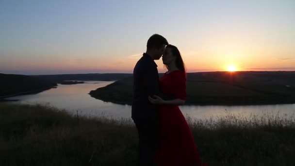 Verliebte Paare küssen sich am Ufer des Flusses. Sonnenuntergang. — Stockvideo