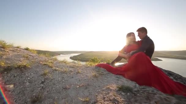 Casal apaixonado sentado na beira dos rios. Luz do pôr do sol . — Vídeo de Stock