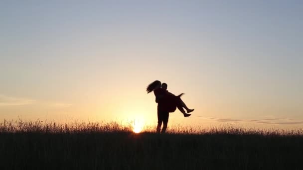 Joven hombre gira en las manos de su mujer en el amor en el borde de los ríos. Luz del atardecer . — Vídeo de stock