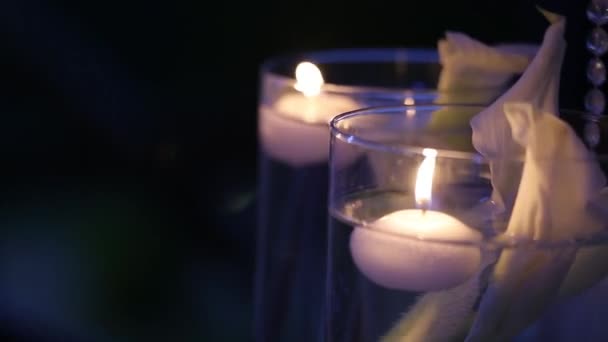 Candles in bottles and glass boxes on the wedding ceremony outdoors late in evening. Romantic lights. — Stock Video