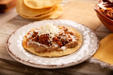 Köfteli tinga tostu, Meksika usulü geleneksel ev yapımı et, öncelikle acı biberli ve bol soğanlı, geleneksel olarak Tostadas 'ta yenir (kızarmış mısır tortillası).).