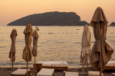 Güneş şemsiyesi, ufuk, adada boş şezlong, sakin bir deniz arka plan üzerinde kapalı.