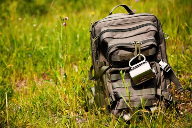 Green Backpack with Camping Gear in Open Field, Tourist and Military Style, Green Tourism Concept