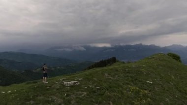 Bir uçurumun üzerinde duran ve dağlar panorama izlerken uzun yürüyüşe çıkan kimse