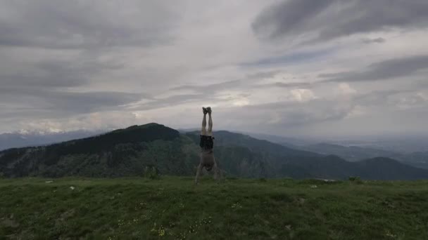 Człowiek robi handstand na zewnątrz na klifie — Wideo stockowe