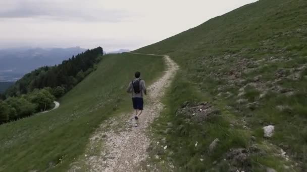 Молодой спортсмен бежит по тропинке в горах — стоковое видео