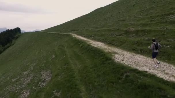 Joven deportista corriendo por un sendero en las montañas — Vídeos de Stock