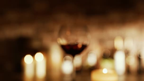 Sommelier vypít sklenku červeného vína ve sklepě, sbírka lahví a zapálených svíček: víno kultury a vinařství koncepce